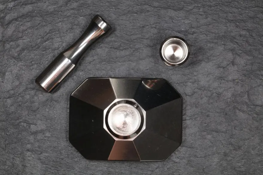 The pestle and the cup above, the faceted base below, on dark slate