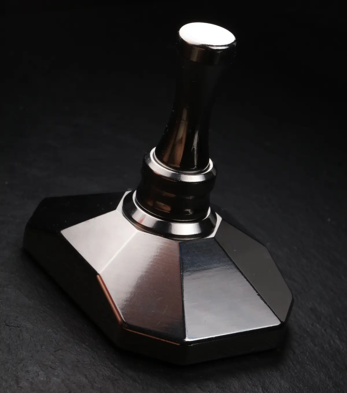 The assembled crusher facing the camera, the pestle rising from the faceted base